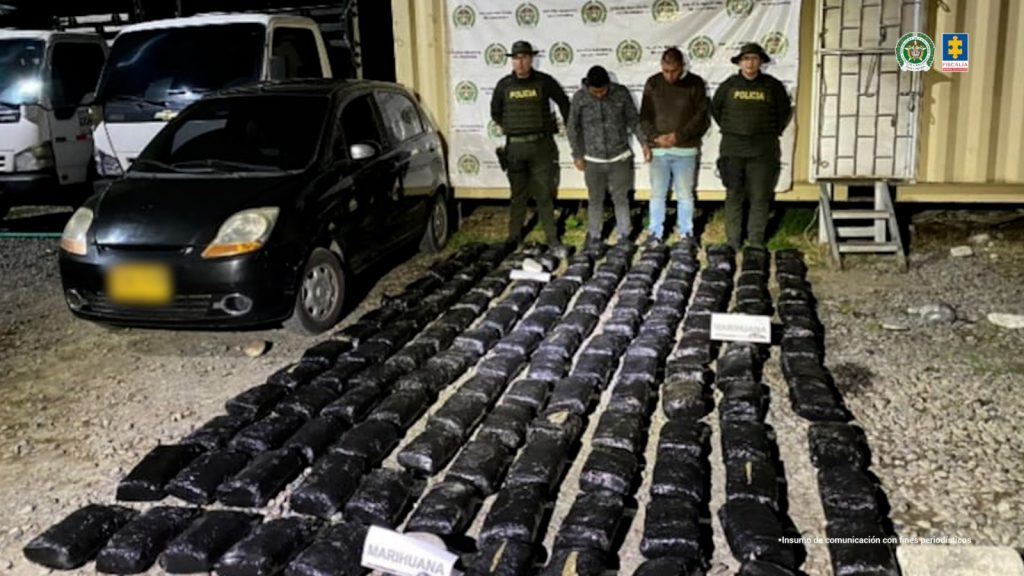 En la fotografía aparecen los dos capturados junto a dos agentes de la Policía Nacional. En la parte posterior está el cargamento de marihuana y el vehículo incautado