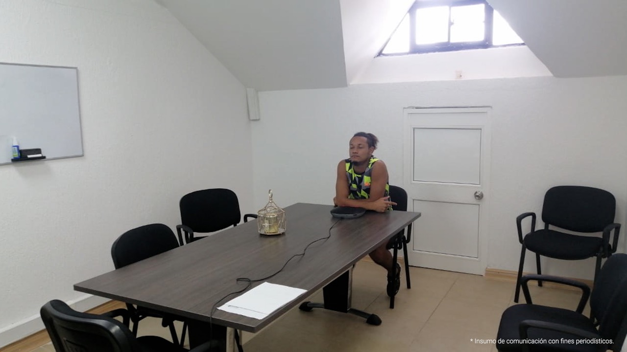 En la imagen aparece el condenado sentado, frente a él una mesa. La habitación en la que se encuentra es blanca.