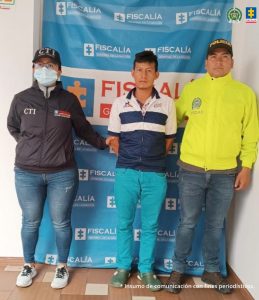 En la fotografía aparecen el capturado junto a un servidor del CTI y un agente de la Policía Nacional. En la parte superior está un banner de la Fiscalía General de la Nación