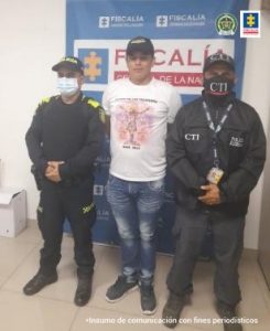 En la fotografía se aprecia de pie y con los brazos atrás a Eider Arnover Ruíz Londoño. Viste camiseta de manga corta blanca y jean azul; así como gorra y zapatillas negras. Al lado izquierdo de él hay una servidora del CTI de la Fiscalía y al lado derecho una uniformada de la Policía Nacional. Detrás de ellos hay un pendón institucional de la Fiscalía.