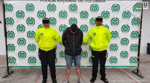 Fiscal Mancera, Fiscal Martha Mancera, Martha Mancera, Fiscalía General de la Nación El capturado está de frente a la cámara con la cara agachada, viste una chaqueta oscura y tiene un short de jean, custodiado por dos uniformados de la Policía Nacional.