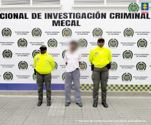Fiscal Mancera, Fiscal Martha Mancera, Martha Mancera, Fiscalía General de la Nación En la fotografía se aprecia de pie y con los brazos atrás a Francisco Plaza Amaya. Viste camisa blanca de manga corta y cuello, pantalón de dril color y zapatos grises. A lado y lado de él hay uniformados de la Policía Nacional. Detrás de ellos hay un pendón institucional de la Policía.