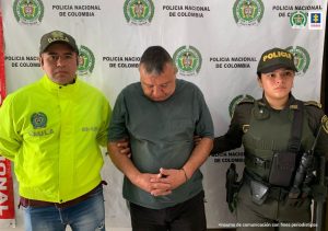 Fiscal Mancera, Fiscal Martha Mancera, Martha Mancera El capturado tiene un buso de color verde, tiene sus manos adelante esposadas y está custodiado por dos uniformados de la policía.