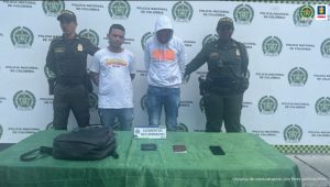 Martha Mancera, Fiscal Mancera, Fiscal Martha Mancera En la fotografía aparecen de pie y con los brazos atrás Óscar Julián Muñoz Cárdenas y Edwin Jhoan Giraldo González. Uno viste camiseta blanca de manga corta con estampado a la altura del pecho y jean azul. El otronviste buso de mana larga y capucha de color gris; jean azul. A lado y lado de ellos hay uniformados de la Policía Nacional. Delante de ellos hay una mesa con mantel verde y sobre ella hay un maletín negro y tres elementos. Asimismo, un letrero que dice: ‘Elementos recuperados’. Detrás de ellos hay un pendón institucional de la Policía.