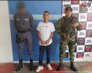 En la fotografía aparece un hombre capturado, acompañado de un  uniformados de la Policía y del Ejército  Nacional.  En la parte posterior un banner con logos de la entidad.      