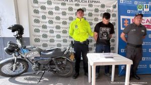 Fiscal Mancera, Fiscal Martha Mancera, Martha Mancera, Fiscalía General de la Nación En la imagen se ve una persona detenida bajo custodia de un integrante de la Policía y otro del CTI de la Fiscalía. A su lado una motocicleta decomisada y al frente suyo una mesa con un celular incautado.