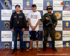 Fiscal Mancera, Fiscal Martha Mancera, Martha Mancera, Fiscalía General de la Nación En la foto se ve una persona detenida bajo custodia de integrantes del CTI y el Ejército Nacional. Detrás suyo un backings institucionales.