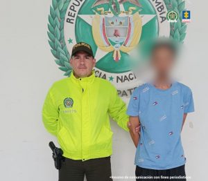 En la imagen está el presunto responsable del homicidio de su hijastro con el roestro distorsionado y un servidor de la Policía Nacional al lado
