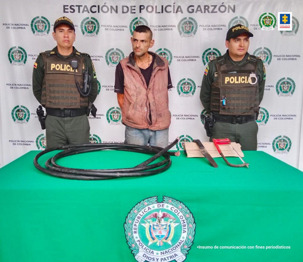 En la fotografía aparece un capturado, junto a personal de Policía Nacional. En la parte posterior de la imagen se ven banners de Policía Nacional y la Fiscalía General de la Nación.