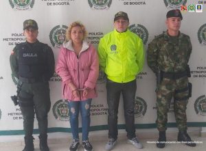 En la fotografía aparece un capturado, junto a personal de Fiscalía General de la Nación, Policía Nacional y Ejército Nacional. En la parte posterior de la imagen se ven banners de Ejercito Nacional, Policía Nacional y la Fiscalía General de la Nación.