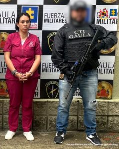 En la imagen se encuentra la procesada con un servidor del CTI, y el parte de atrás un pendón con los logos de la Fiscalía General de la Nación y el Gaula del Ejército Nacional.