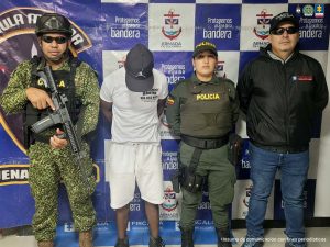 En la fotografía aparecen los capturados junto a un servidor del CTI, tres agentes de la Policía Nacional y un infante de la Armada Nacional. En la parte superior están un banner de la Armada Nacional y otro banner de la Policía Nacional