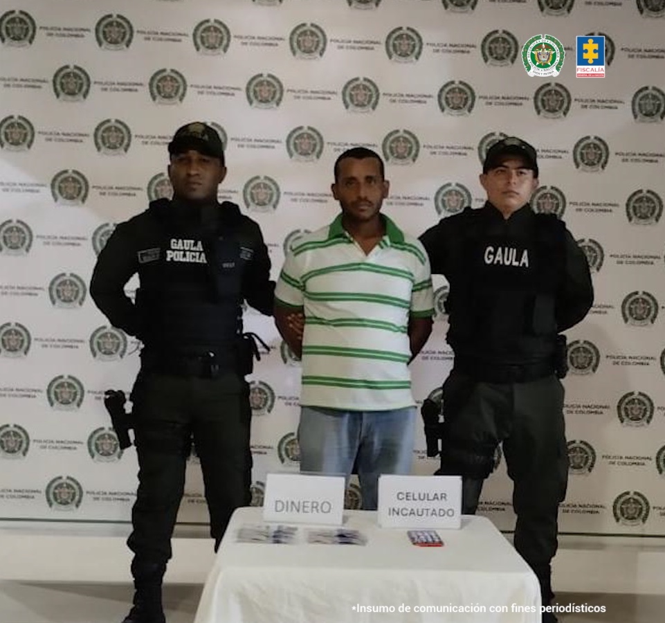 En la imagen se aprecia una persona de camiseta de rayas entre dos uniformados del Gaula de la Policía.