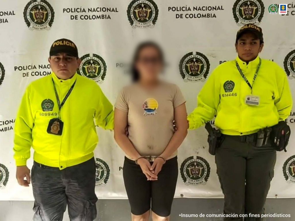 Se observa a una mujer de blusa color crema esposada. A su lado dos Policías quienes la capturaron por presuntamente haberle arrojado agua caliente a su hija de 6 años.