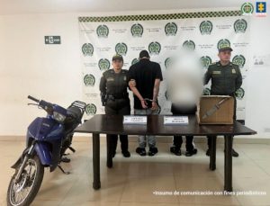 En la fotografía aparece de pie, de espaldas a la cámara, con los brazos atrás y esposado Nico Daniel Molina Escalante. Viste com camiseta de mangas corta, de color negro y pantalón gris. En los extremos hay uniformados de la Policía Nacional. En la parte delantera hay una mesa y sobre ella hay un contenedor de cartón que contiene un cuchillo. Asimismo, hay dos letreros borrosos y el extremo izquierdo de la fotografía se aprecia una motocicleta. En la parte posterior hay un pendón institucional de la Policía.