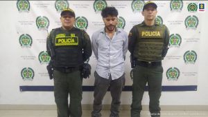 En la fotografía se aprecia de pie, con los brazos atrás a Nicolás Arango Loaiza, alias Nico. Viste camisa azul clara con botones adelante, pantalón gris oscuro y zapatos oscuros.  Al lado izquierdo de ellos hay dos uniformados de la Policía. En la parte posterior hay un pendón institucional de la Policía.