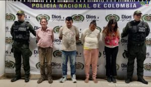capturados de frente custodiados por policías. Detrás banner de la Policía Nacional.