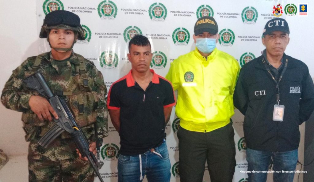 En la foto aparece de pie y con los brazos atrás, Norvey Gutiérrez Ladino, alias ‘Frank’. Viste camisa de manga corta negra con ribetes color naranja y jean azul. A su lado derecho hay un uniformado del Ejército y a su derecha hay un uniformado de la Policía y del CTI de la Fiscalía. Detrás de ellos hay un pendón institucional de la Policía.