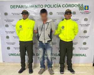 En la imagen aparece una persona con capucha entre dos policías uniformados. 