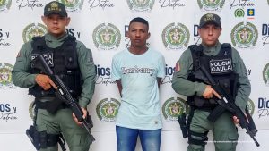 En la imagen aparece una persona de suéter verde, entre dos uniformados de la Policía Nacional.