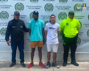 En la fotografía aparecen dos hombres capturados, acompañados de un servidor del CTI, y un uniformado de La Policía Nacional. En la parte posterior un banner con logos de la entidad.