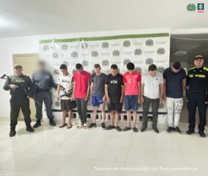 En la foto aparece siete de los nueve capturados custodiados un sevidor del CTI y dos uniformados de la Policía Nacional. En la foto también aparece de fondo un backing de la Policía Nacional.