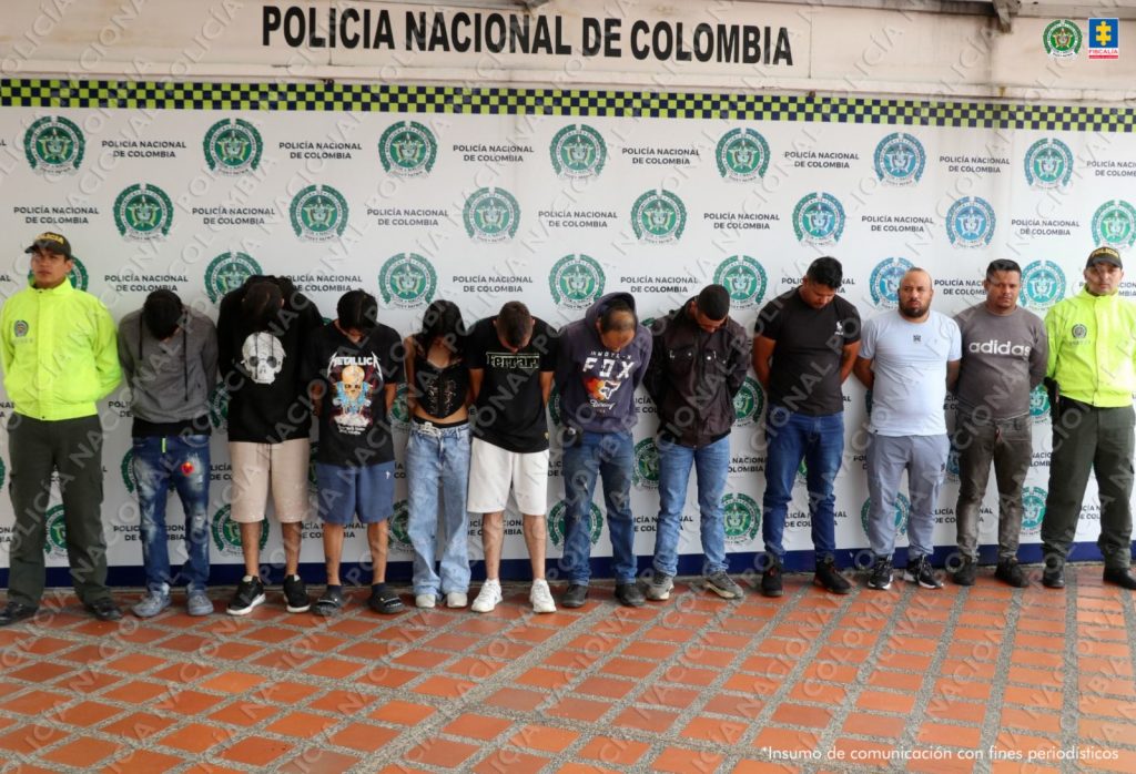 Se observan 10 personas capturadas, en fila y de frente. A cada costado un funcionario de la Policía Nacional. Atrás, un pendón de Policía Nacional.