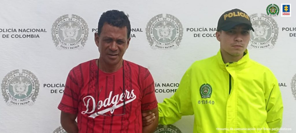 En la fotografía el presunto agresor de 56 años, tiene una camisa roja y se encuentra en compañía de un agente de la Policía Nacional.