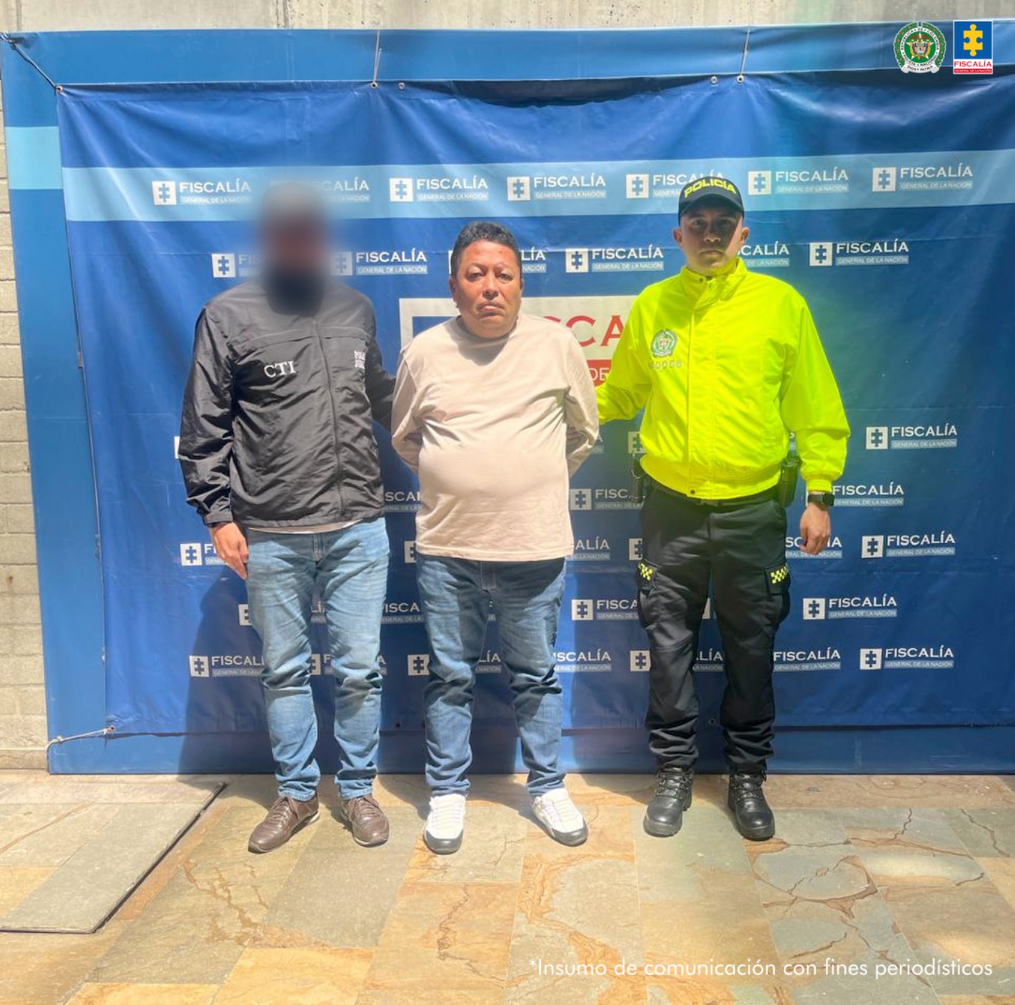 En la imagen se ve el procesado con un servidor del CTI y otro de la Policía Nacional y al fondo un pendón azul de la Fiscalía.