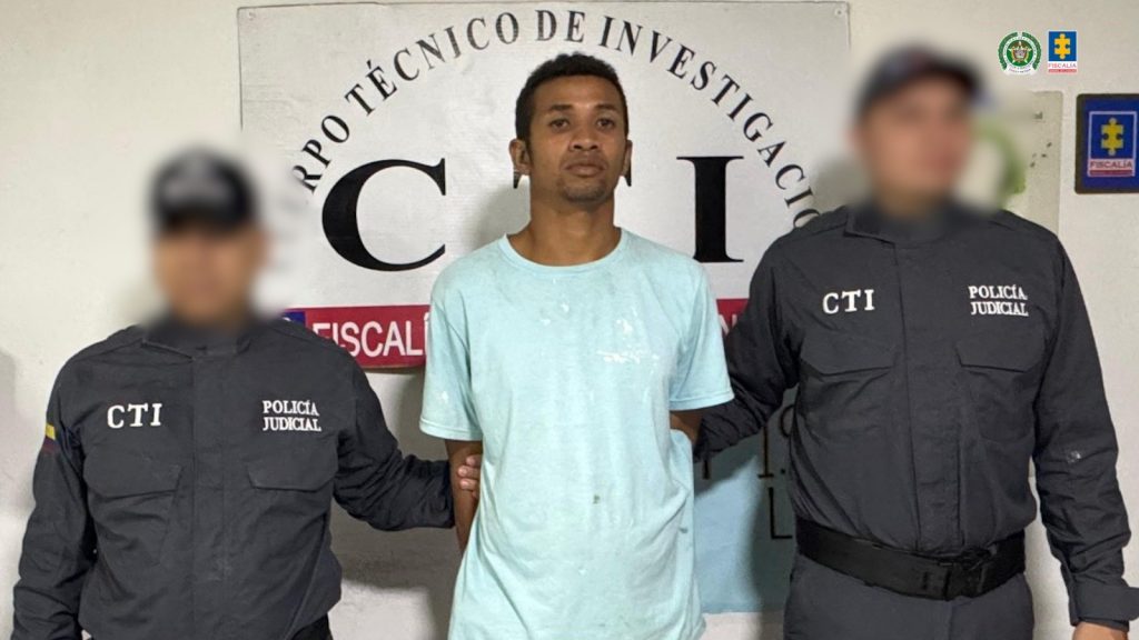 En la imagen aparece una persona de camiseta azul turquesa, entre dos uniformados del CTI.