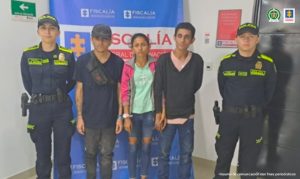 Se visualiza a los capturados junto a dos uniformados de la Policía Nacional. En la parte posterior se ubica el banner que identifica a la Fiscalía General de la Nación.