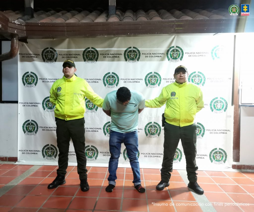 en la fotografía se encuentra el detenido en medio de dos funcionarios de la policía con un baking de la institución