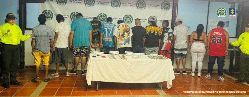 En la fotografia se puede ver a los 12 detenidos de espaldas y a los costados dos funcionarios de la policia