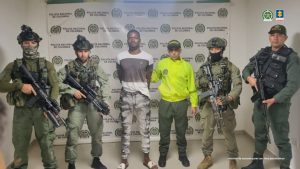 En la imagen aparece el capturado, de estatura alta y esposado , en compaía de un uniformado de la Policía Nacional y dos integrantes del Ejército 