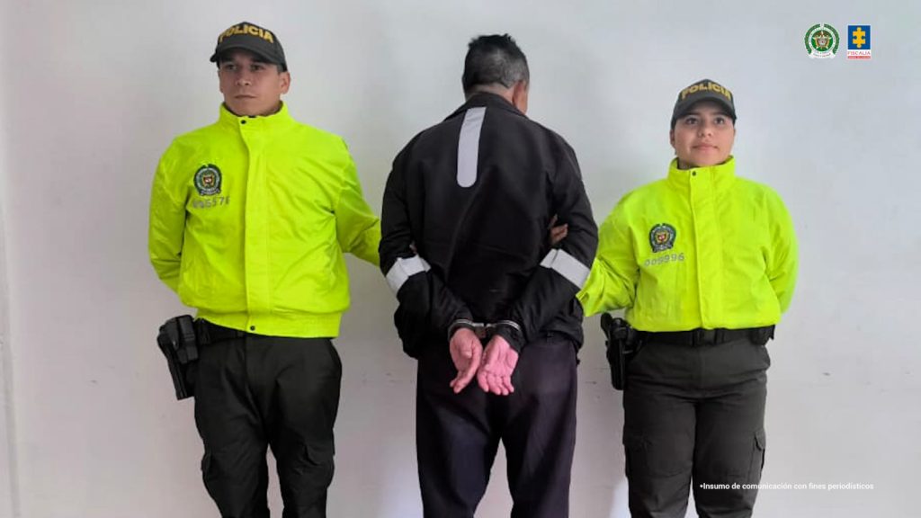 En la imagen se ve a un honbre capturado de espaldas en compañía de dos uniformados de la Policía.