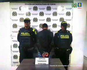 En la fotografía se encuentran tres personas dos de ellas uniformados de la Policía Nacional y el capturado que se encuentra de espaldas.
