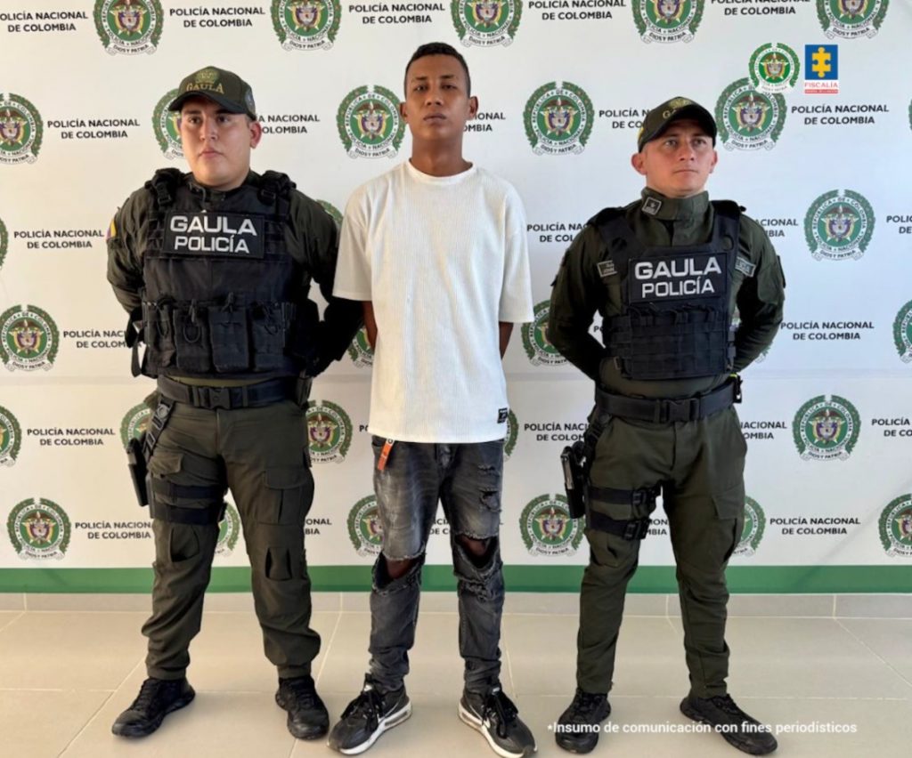 El capturado aparece con sus manos esposadas a la espalda, custodiado por dos uniformados del GOES de la Policía Nacional.