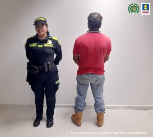 capturado de espaldas custodiado por una policía.