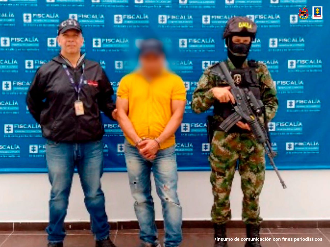capturado esposado, custodiado por uniformados de la Policía. Detrás banner de la Policía