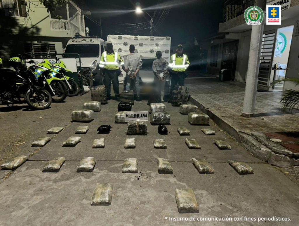 En la foto aparece la pareja judicializada, de espaldas a la cámara y con los brazos atrás esposados, en una vía pública. A lado y lado de ellos hay uniformados de la Policía Nacional. En el piso se parecían varios paquetes rectangulares.
