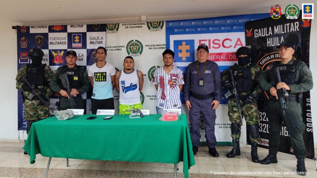 En la fotografía aparecen tres capturados, junto a personal de Policía Nacional, Ejército Nacional y Fiscalía General de La Nación. En la parte posterior de la imagen se ven banners de Ejército Nacional, Policía Nacional y la Fiscalía General de la Nación.