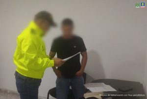En la foto se observa al uniformado de la Policía Nacional cuando le está leyendo la orden de captura al subintendente Julián Hernando Urquijo Castillo. El procesado tiene una camiseta negro y un jean.