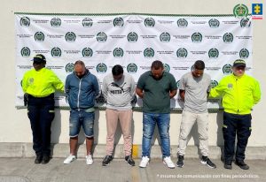 En la fotografía se aprecia de pie y con la cabeza agachada a los cuatro patrulleros de la Policía. A los extremos de ellos hay uniformados de la Policía Nacional y detrás de ellos un pendón de esa misma institución.