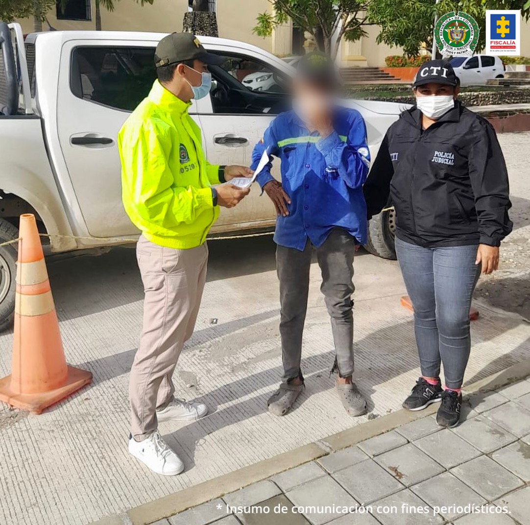 En la imagen se ve una persona capturada entre un policía y una investigadora del CTI de la Fiscalía.