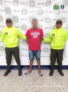 En la imagen se ve una persona detenida entre dos uniformados de la Policía. 