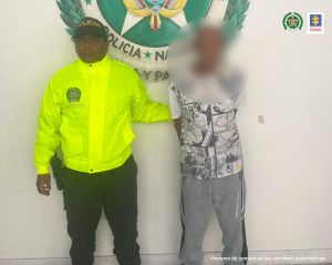  En la imagen está el hombre de 77 años con el rostro distorsionado y acompañado de un servidor de la Policía Nacional