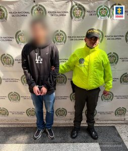 En la imagen está el procesado con un servidor de la Policía Nacional y un pendón de la misma entidad en la parte de atrás
