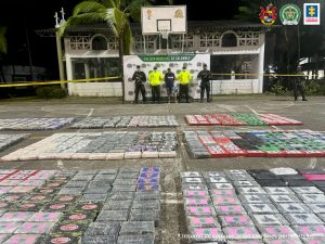 En la imagen aparece el procesado acompañado de personal del Ejército y la Policía Nacional. En el piso se encuentran numerosos paquetes, al parecer, con la droga incautada.
