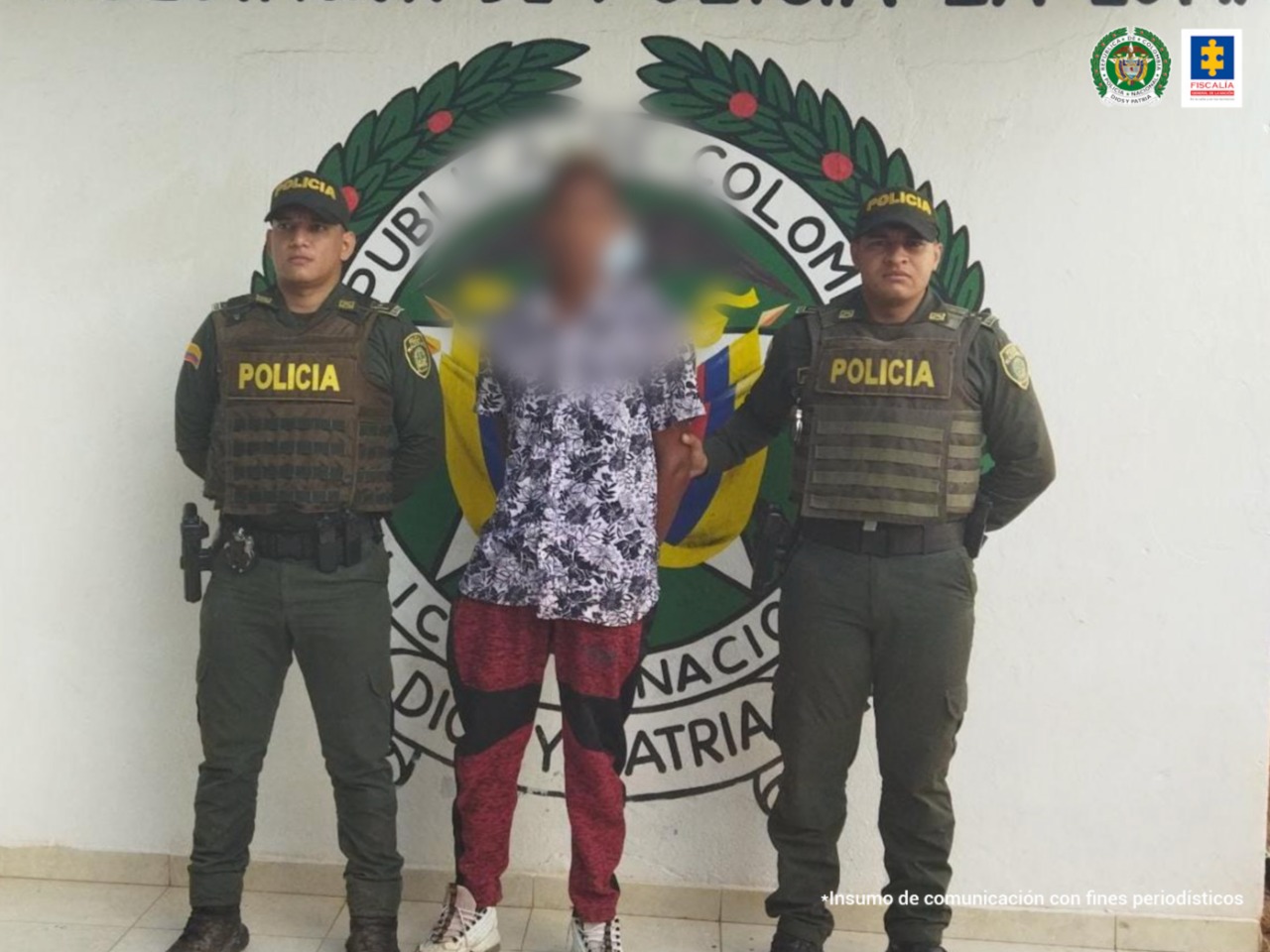 En la fotografía aparece una persona capturada, junto a dos uniformados de la Policía Nacional. En la parte posterior se ve un banner de la misma entidad.