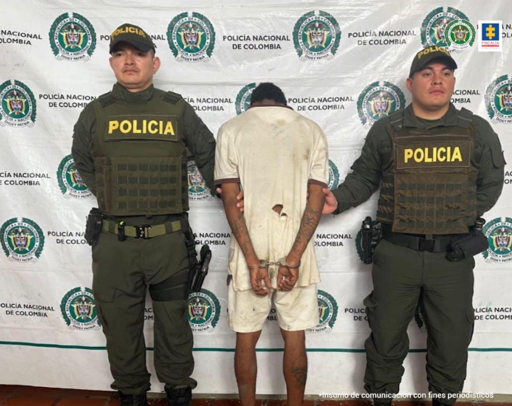 En la foto aparece de espaldas el procesado, acompañado de dos uniformados de la policía.